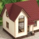 Ein Hausmodell mit gepflasterter Grundfläche, Wiese und Modellbäumen | Notverkauf