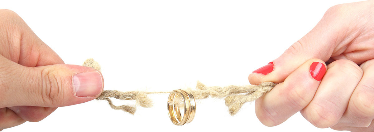 Zwei Hände ziehen an einem Strick, der reißt und an dem ein Ehering hängt | Wohnrecht Scheidung