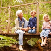 Großeltern sitzen mit Enkeln auf einer Holzbrücke im Wald - Wohnen im Alter
