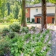 Ein Blumenbeet und mehrere Bäume vor einem Einfamilienhaus mit Zufahrt - Immobilienwert