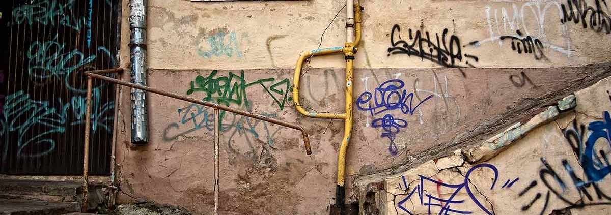 Eine alte Hauswand mit Graffiti und rostigem Treppengeländer und Gitter - Sanierungsstau