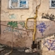 Eine alte Hauswand mit Graffiti und rostigem Treppengeländer und Gitter - Sanierungsstau
