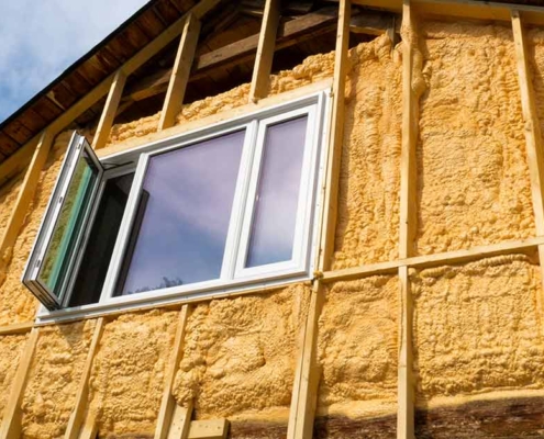 Eine Häuserfassade mit offener Dämmung und offenem Fenster - Energetische Sanierung