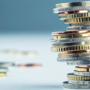 Ein Stapel Münzen vor einem blauen Hintergrund - Anschlussfinanzierung Immobilienkauf