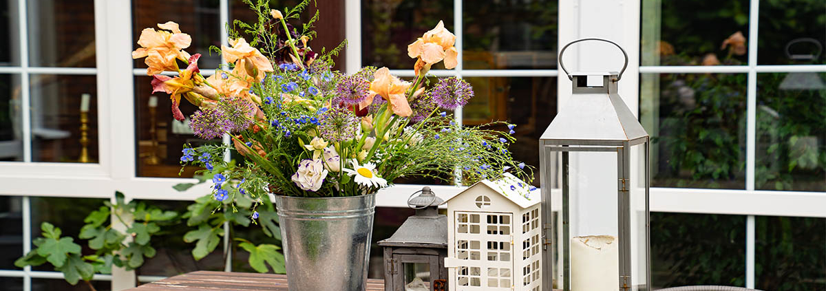 Ein Holztisch mit Blumenstrauß und Kerzenhaltern - Jetzt Immobilie kaufen