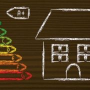 Auf einen Holztisch sind mit Kreide ein Haus und links daneben die Energieeffizienzklassen gemalt | Energetische Sanierung