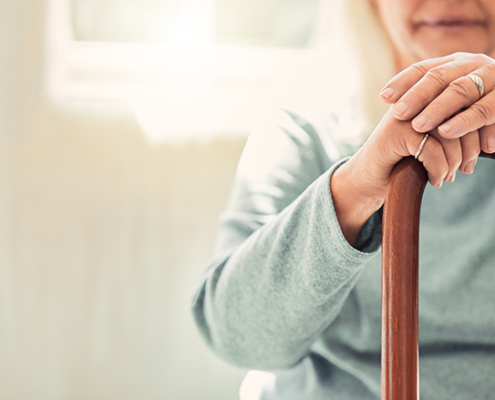 Growing old is inevitable, but growing up is optional. elderly woman resting her hands on her walking stick while relaxing at home; Wohnen im Alter